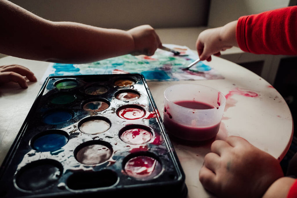 children's hands are painting on a wooden table. - Foto, imagen