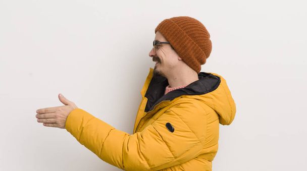 young handsome man with a coat against white wall - Foto, afbeelding