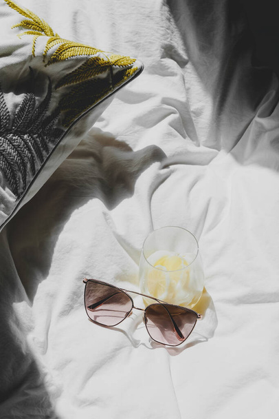 glass of lemonade and glasses with pillow on bed - Foto, Bild