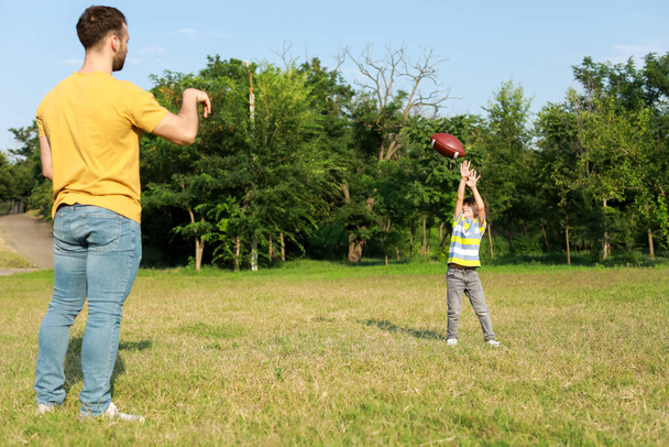 Kleiner Junge spielt mit seinem Vater Rugby auf dem Feld - Foto, Bild
