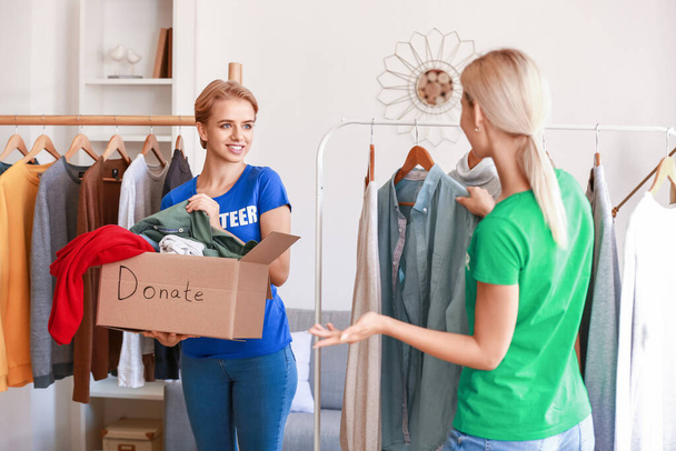 Female volunteers picking clothes for donation in room - Foto, Imagem