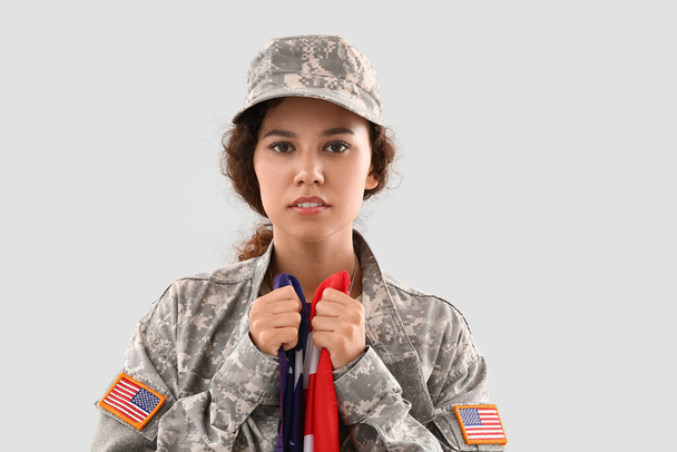 Soldado feminino afro-americano com bandeira dos EUA em fundo claro - Foto, Imagem