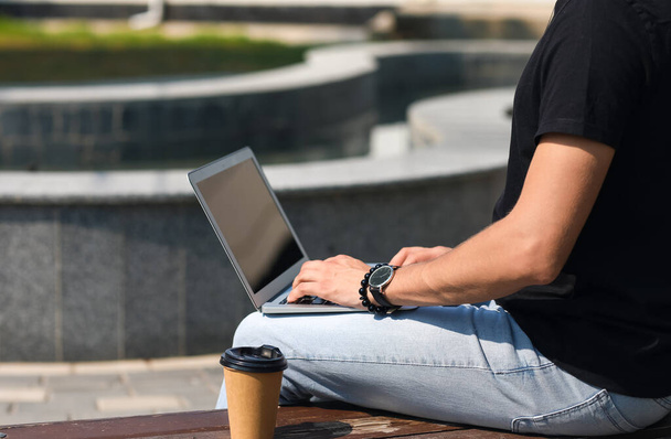 Jovem usando laptop no banco ao ar livre - Foto, Imagem