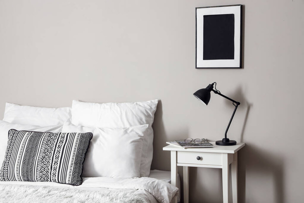 Bedside table with modern lamp near light wall - Photo, Image