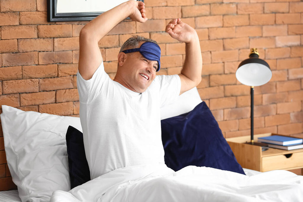 Mature man with sleep mask in bed - Photo, Image