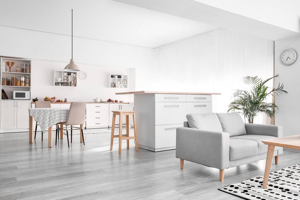 Sisustus kevyt moderni keittiö, jossa valkoinen laskurit, ruokapöytä ja sohva - Valokuva, kuva