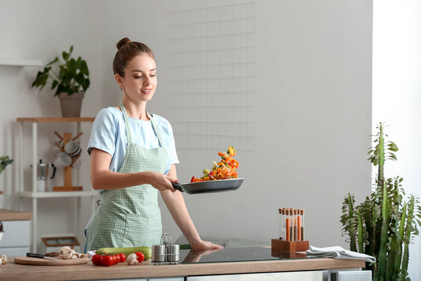 Beautiful housewife frying vegetables in kitchen - Foto, Imagem