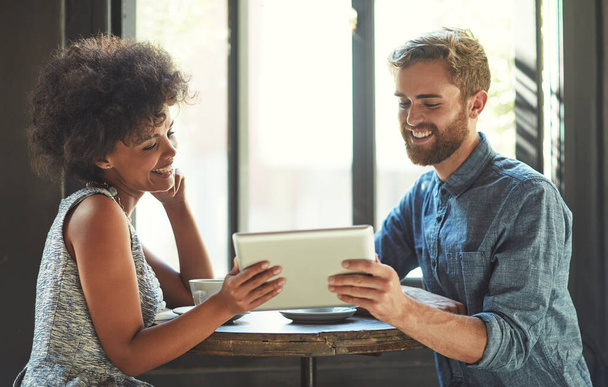 Partilhar o amor online. Tiro de um jovem casal usando um tablet digital juntos em uma data de café. - Foto, Imagem