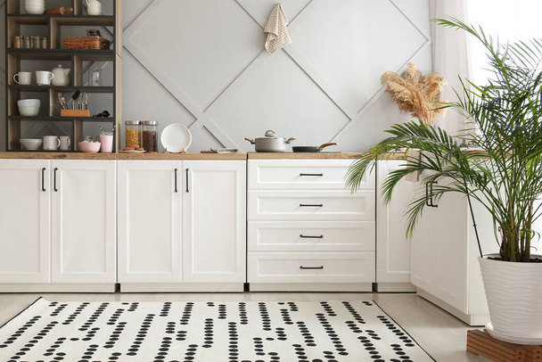 Interior de la cocina ligera con mostradores blancos, estanterías y alimentos - Foto, Imagen