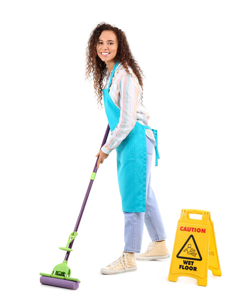 African-American female worker of cleaning service with mop and caution sign on white background - Foto, Imagen