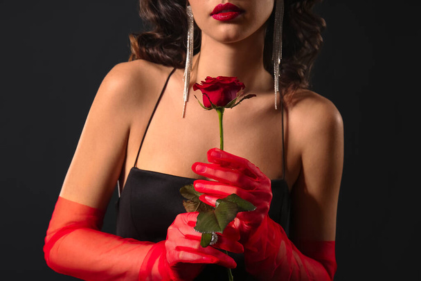 Elegante Frau mit roten Handschuhen und stylischem Schmuck auf dunklem Hintergrund - Foto, Bild