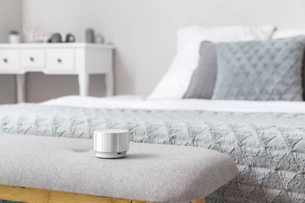 Bezprzewodowy przenośny głośnik na ławce w pobliżu łóżka w pokoju - Zdjęcie, obraz