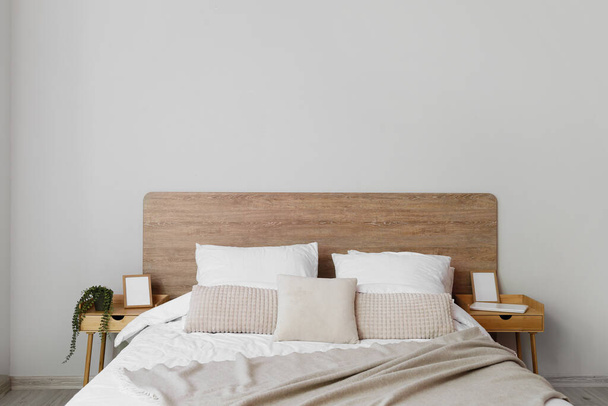 Comfortable bed and nightstands near light wall - Фото, зображення