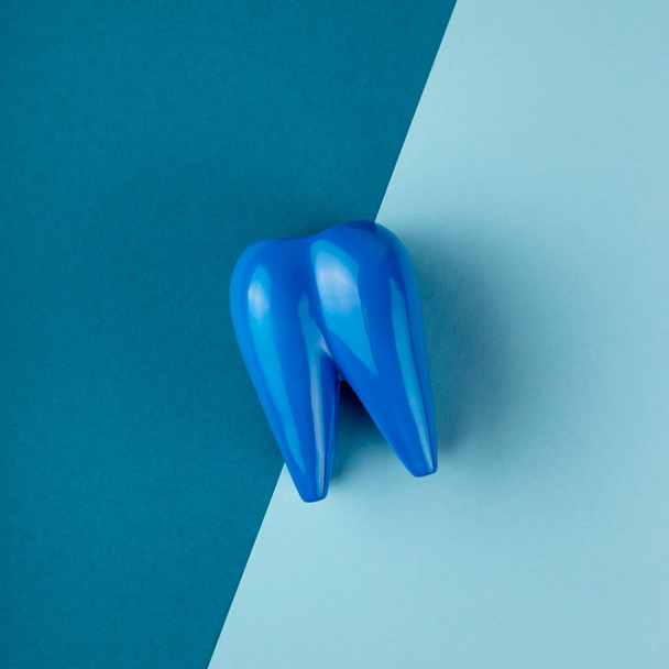 Large blue tooth lies on combined blue background.  - Foto, imagen