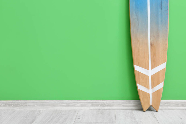Modern surfboard near green wall in room - Photo, image