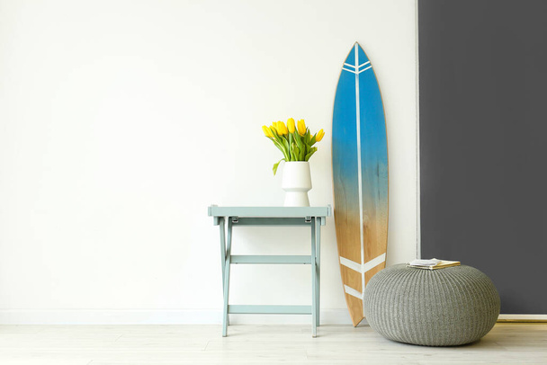 Surfboard, stůl a váček u stěny - Fotografie, Obrázek