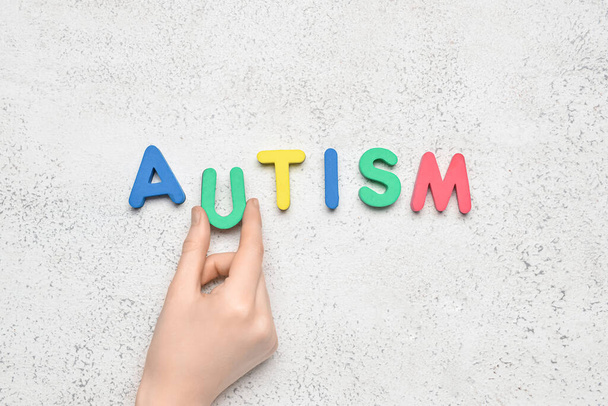 Woman with word AUTISM on light background - Foto, Imagen