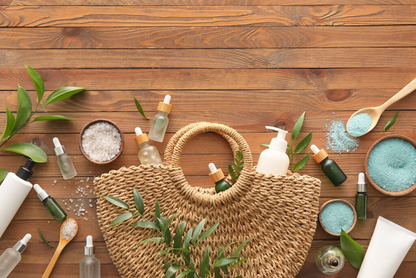 Wicker bag with natural cosmetics on wooden background - 写真・画像