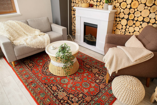 Interieur van gezellige woonkamer met vintage tapijt, tafel en open haard - Foto, afbeelding