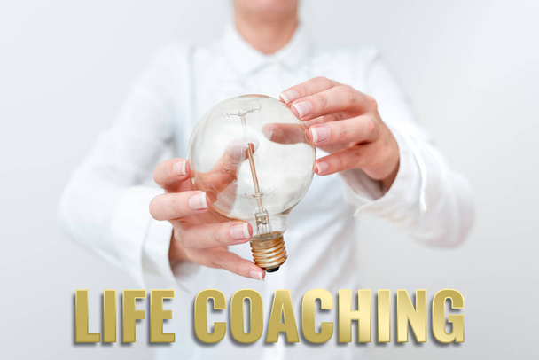 Ręczne pisanie znaku Life Coaching. Podejście biznesowe Improve Lives by Challenges Zachęca nas w naszej karierze Pani w stroju trzymając lampę obiema rękami prezentując nowe pomysły technologiczne - Zdjęcie, obraz