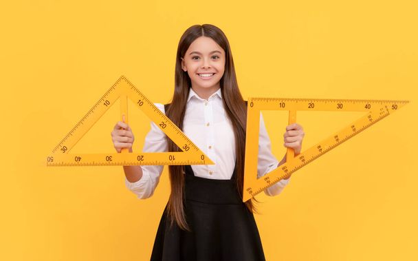 glimlachende tiener meisje houden driehoek. terug naar school. algebra en meetkunde. kind studie wiskunde. - Foto, afbeelding