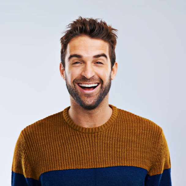 Gewoon lachen. Studio shot van een gelukkige en knappe man lachen tegen een grijze achtergrond. - Foto, afbeelding