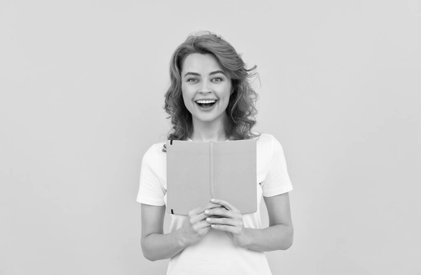 glad woman hold book on yellow background, knowledge - Foto, afbeelding