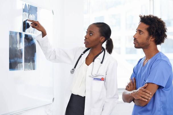 A legjobbtól tanul. Egy röntgent tanulmányozó női orvos és férfi ápolónő képe.. - Fotó, kép