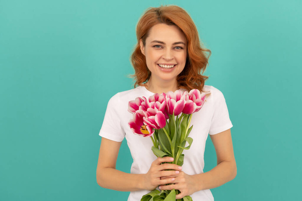 смеющаяся женщина с цветочным букетом тюльпана на синем фоне - Фото, изображение
