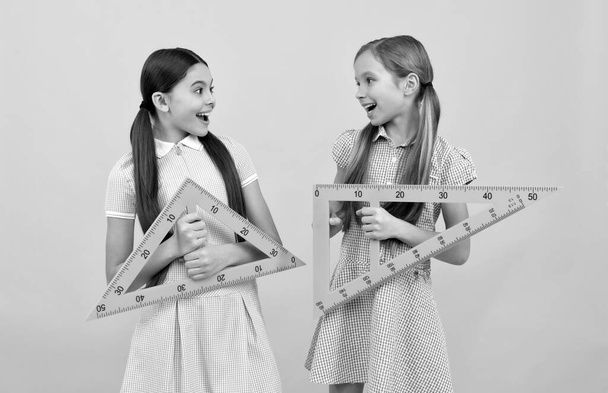 Дети счастливого школьного возраста держат треугольные линейки для урока геометрии, обратно в школу - Фото, изображение