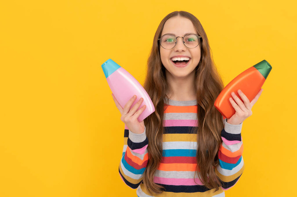 presenting cosmetic product for teen. kid in glasses choose shower gel. happy teen girl - Photo, Image