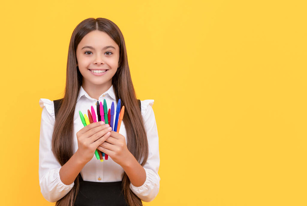 Glückliches Mädchen Kind halten Filzstifte gelb Hintergrund, Schulspitze - Foto, Bild