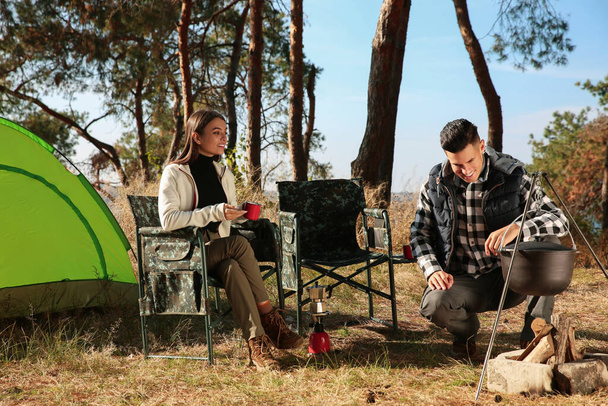 Couple resting near bonfire at camping site - Photo, image