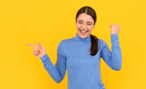 mujer riendo retrato señalando los dedos en el espacio de copia fondo amarillo, éxito - Foto, imagen