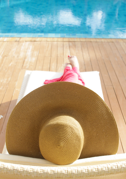 プールのそばでリラックスした帽子の若い美しい女性 - 写真・画像