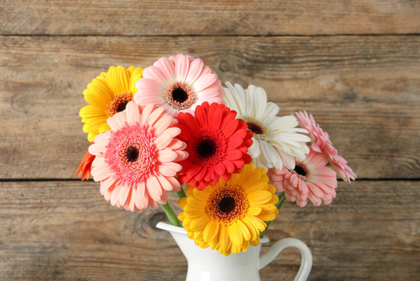 Bouquet of beautiful colorful gerbera flowers in vase on wooden background - Foto, afbeelding