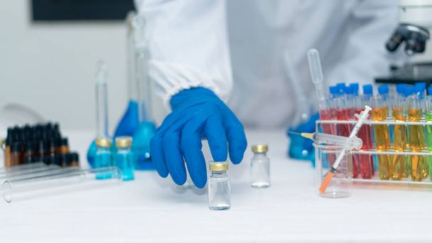 Vědecký ruční nástroj držící láhev s laboratorním sklem v pozadí chemické laboratoře. Koncepce výzkumu a vývoje ve vědeckých laboratořích Medicína a biotechnologie - Fotografie, Obrázek