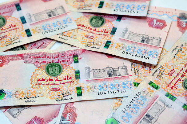 Focus selettivo di una pila di 100 AED cento banconote Dirhams valuta degli Emirati Arabi Uniti Emirati Arabi Uniti con una foto di Al Fahidi Fort, Una pila di denaro Emirates isolato su sfondo bianco  - Foto, immagini