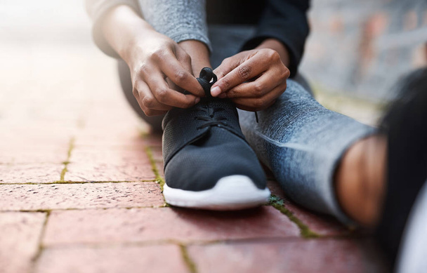 Es hora de moverse. Recorte de una mujer atándose los cordones de los zapatos antes de una sesión de entrenamiento. - Foto, Imagen