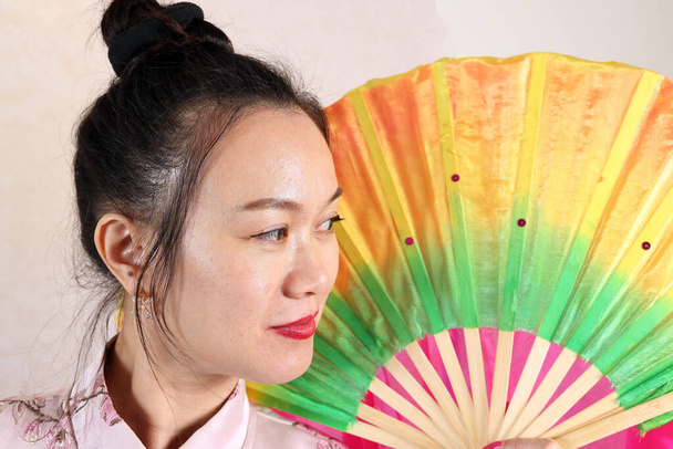 Origem asiática mulher atraente meia idade vestindo cheongsam colorido tinha ventilador - Foto, Imagem