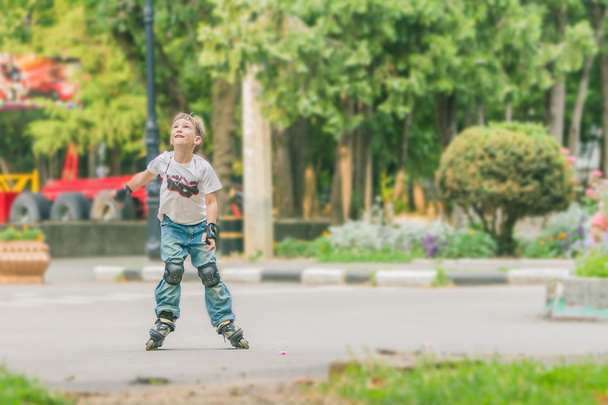 young happy boy faving fun on roller scates on natural backgroun - Fotó, kép