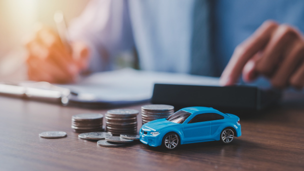 Mężczyzna korzystający z kalkulatora z modelem samochodu i pieniędzy na stole, kupujący licząc oszczędności i koszty gazu lub sprzedawca obliczając cenę sprzedaży, wartość pojazdu lub podatków drogowych. - Zdjęcie, obraz
