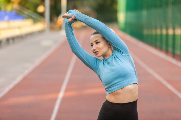 Спортивна жінка робить розминку перед тренуванням на стадіоні. Здоровий спосіб життя
 - Фото, зображення