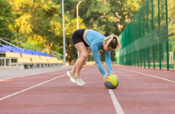 Atlétikai nő gyakorolja dinamika orvosi labdák a stadionban - Fotó, kép