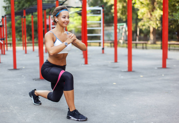 Fiatal izmos nő edz izmokat fitnesz gumiszalagokkal egy sport edzőtéren. Egészséges életmód. Fitness és testépítés. Ellenállási képzés  - Fotó, kép