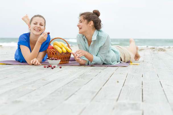 dos mujeres felices jóvenes disfrutando de la vida durante el picnic al aire libre con f
 - Foto, Imagen