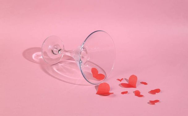 Коктейльный стакан с красными сердцами на розовом фоне. День святого Валентина, 14 февраля - Фото, изображение