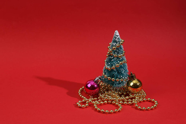 Mini christmas tree with garland and balls on red background - Fotó, kép