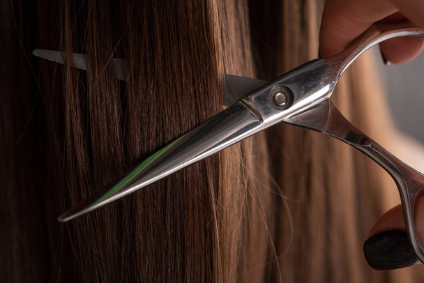 Cut hair of a woman, close up. Hairdresser hold scissors closeup. Haircut concept. - Foto, Imagem