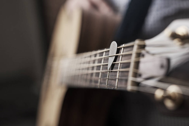 Подними мелодию. Обрезанный кадр неузнаваемого человека, играющего на акустической гитаре дома. - Фото, изображение